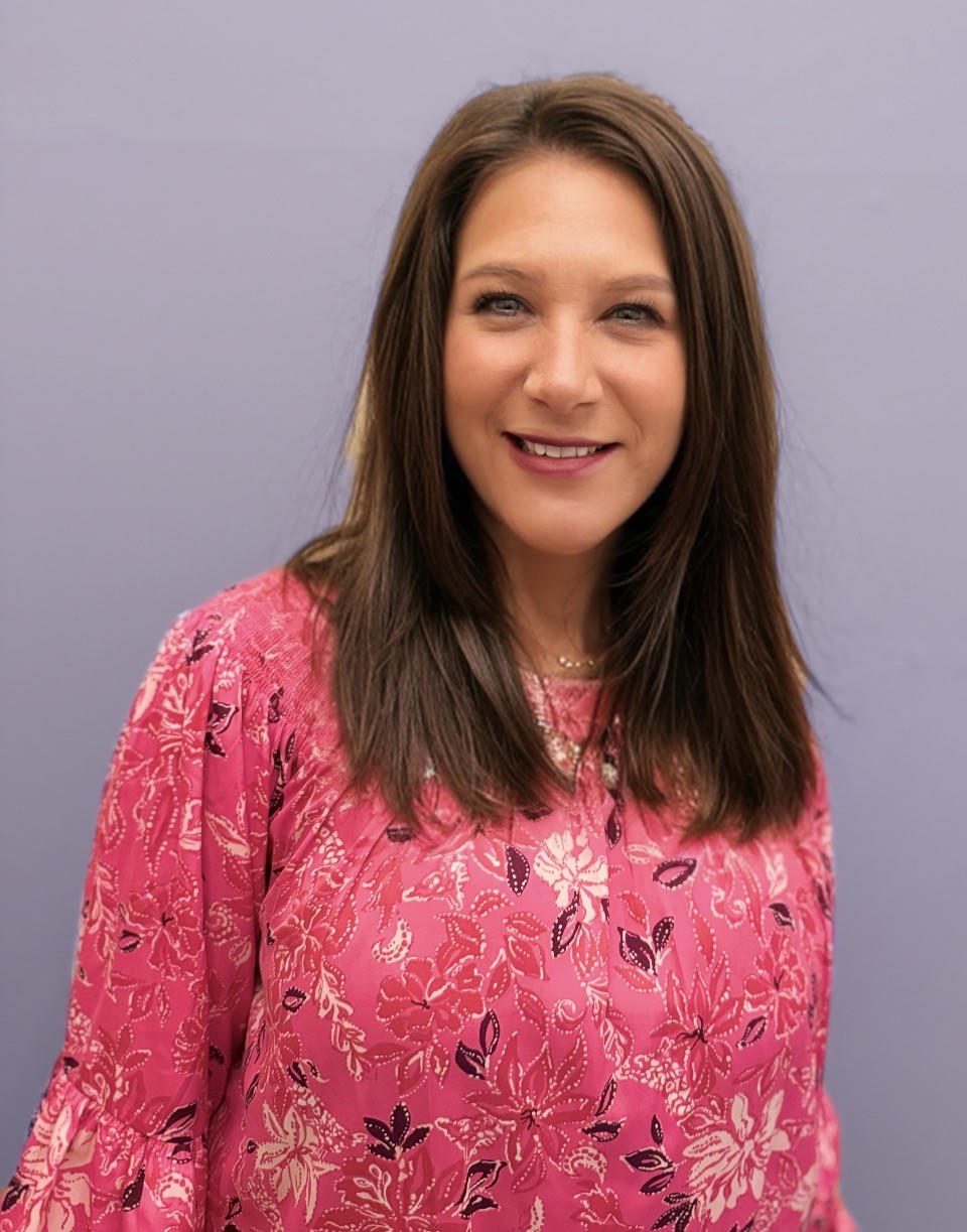 Woman in pink floral top smiling.
