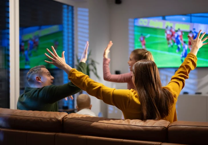 Friends excitedly watching and cheering during a video game session.